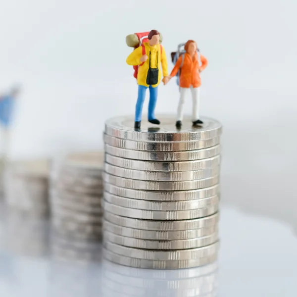 Miniature figures standing on coins, symbolizing financial growth and opportunities in travel loans.