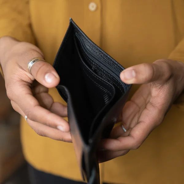 A person holding an empty wallet, symbolizing financial struggle and the challenges of unemployment and loans.