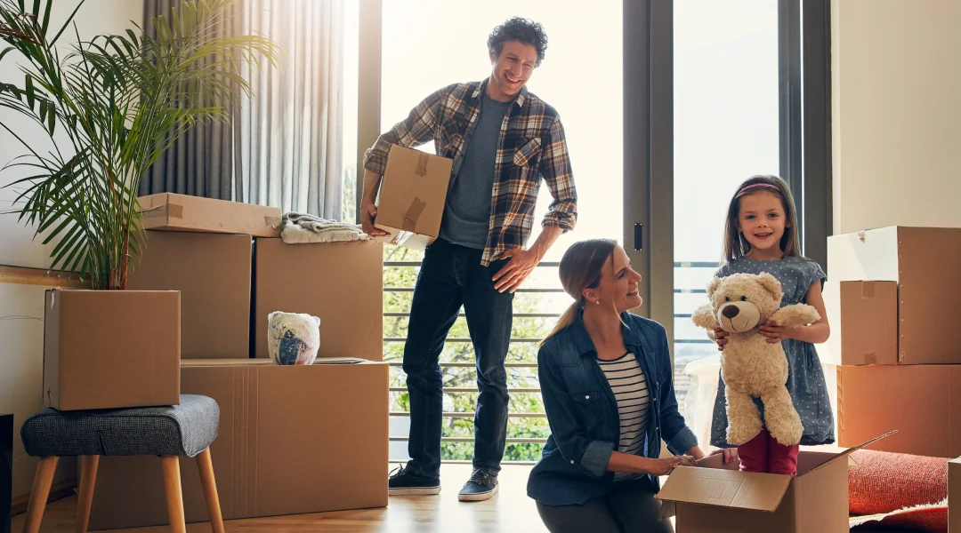 Une famille emménage dans une nouvelle maison, entourée de cartons, symbolisant un nouveau départ. Taux fixe.