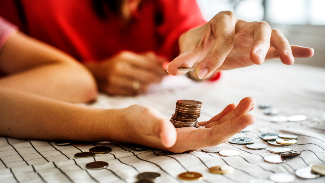 Une femme compte des pièces de monnaie avec ses mains, illustrant l'importance de la gestion financière au Canada.