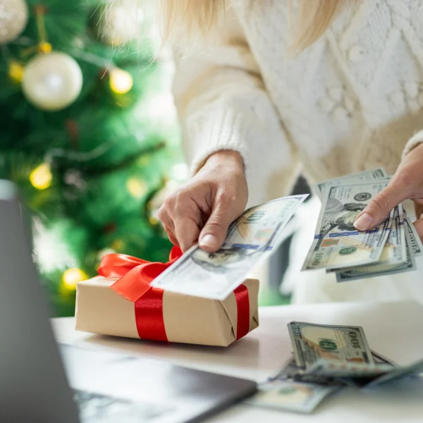 Une femme compte de l'argent devant un ordinateur portable, en lien avec un prêt de Noël.