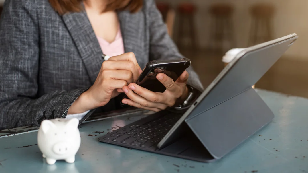 Femme d'affaires utilisant son smartphone et sa tablette dans un café, concentrée sur ses tâches professionnelles.