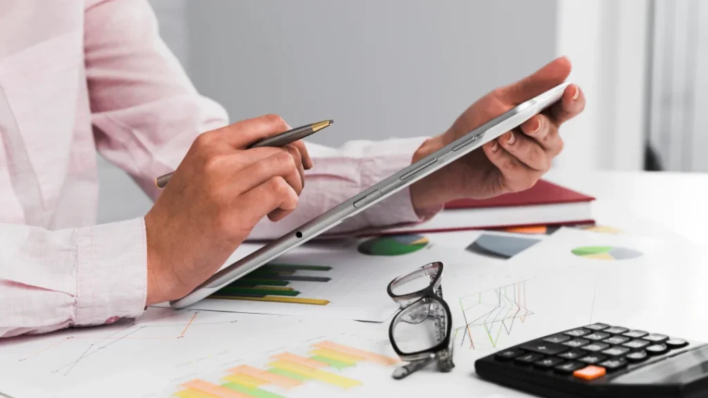 Une personne utilise une tablette avec un stylet et une calculatrice pour la planification financière.