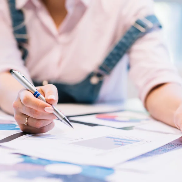 Une femme écrit sur un papier avec un stylo, illustrant le thème de la planification financière.