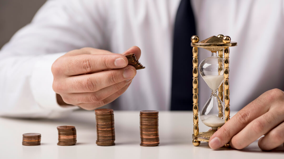 Personne empilant des pièces de monnaie à côté d’un sablier, illustrant un financement d’urgence rapide et sécurisé.