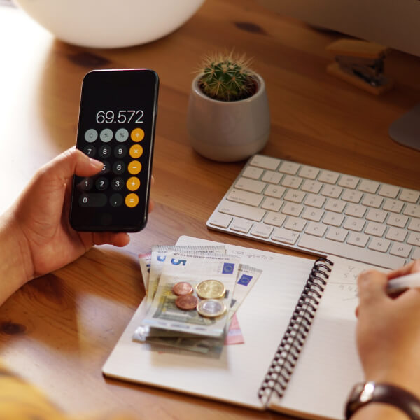 Main utilisant une calculatrice et prenant des notes financières, illustrant la compréhension d’un prêt d’urgence sans justificatif.