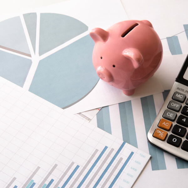 Tirelire posée sur des graphiques financiers avec une calculatrice, représentant l’augmentation de l’intérêt pour les prêts d’urgence au Canada.